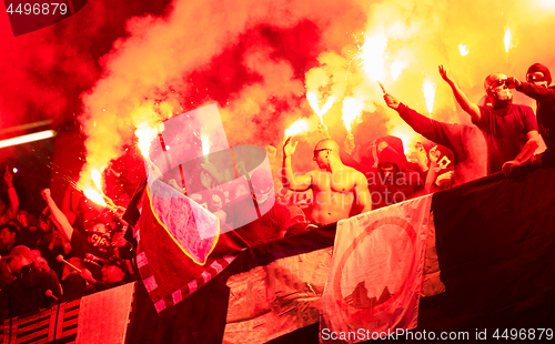 Image of football hooligans with mask holding torches in fire