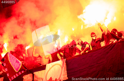 Image of football hooligans with mask holding torches in fire