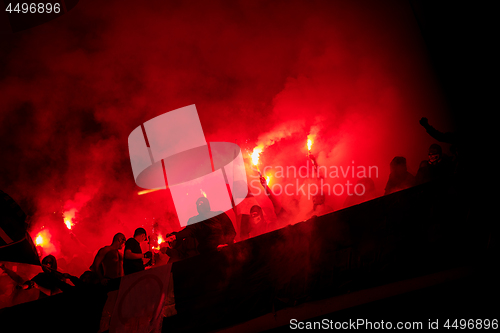 Image of football hooligans with mask holding torches in fire