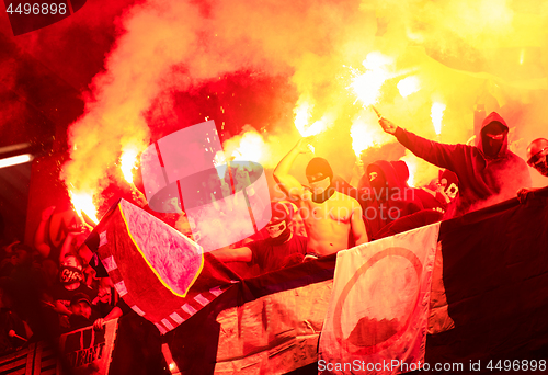 Image of football hooligans with mask holding torches in fire