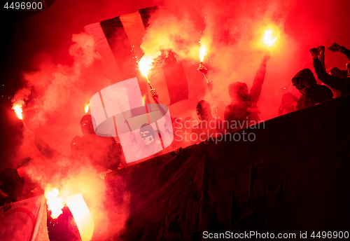 Image of football hooligans with mask holding torches in fire