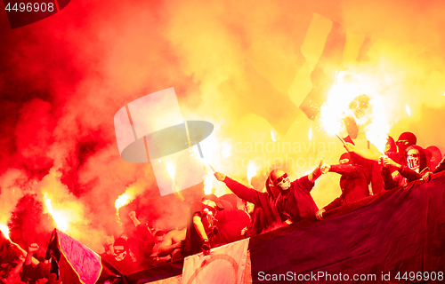 Image of football hooligans with mask holding torches in fire