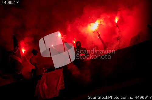 Image of football hooligans with mask holding torches in fire