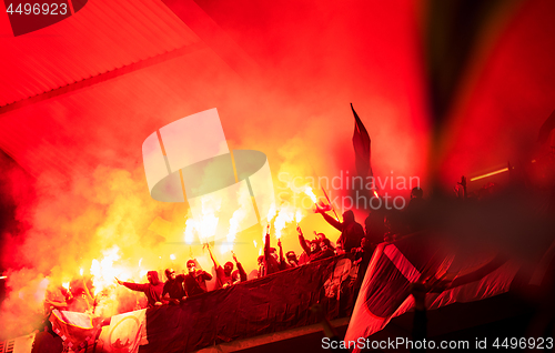 Image of football hooligans with mask holding torches in fire