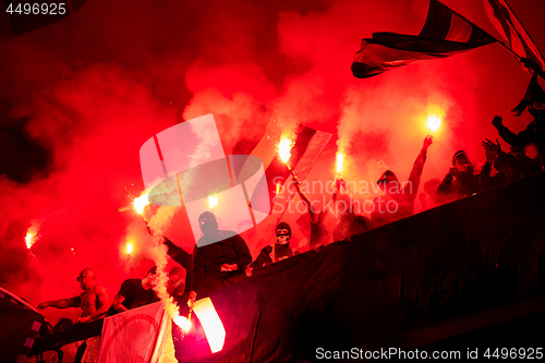 Image of football hooligans with mask holding torches in fire