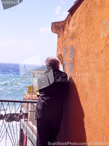 Image of editorial man looking at sea by old waterfront building Riomaggi