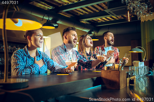 Image of Sport, people, leisure, friendship and entertainment concept - happy football fans or male friends drinking beer and celebrating victory at bar or pub