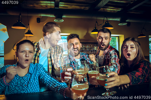 Image of Sport, people, leisure, friendship and entertainment concept - happy football fans or male friends drinking beer and celebrating victory at bar or pub