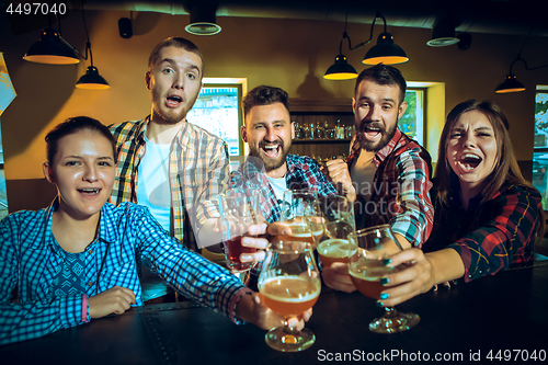 Image of Sport, people, leisure, friendship and entertainment concept - happy football fans or male friends drinking beer and celebrating victory at bar or pub