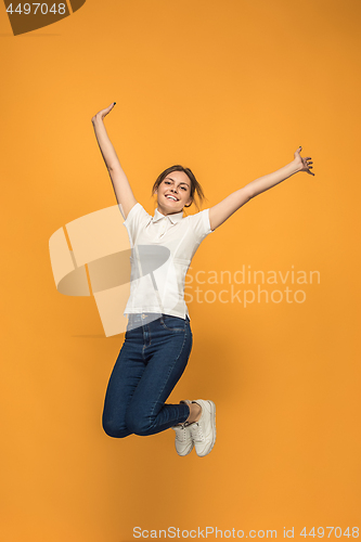 Image of Freedom in moving. Pretty young woman jumping against orange background