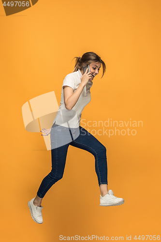 Image of Full length of pretty young woman with mobile phone while jumping