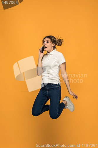 Image of Full length of pretty young woman with mobile phone while jumping