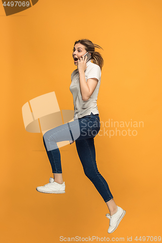 Image of Full length of pretty young woman with mobile phone while jumping