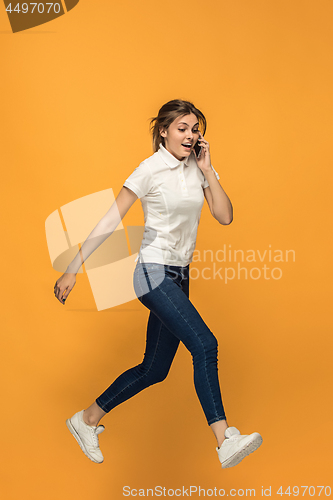 Image of Full length of pretty young woman with mobile phone while jumping