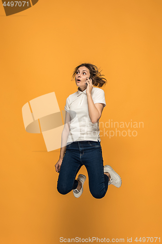 Image of Full length of pretty young woman with mobile phone while jumping