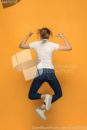 Image of Closeup of young woman\'s body in empty white t-shirt on orange background. Mock up for disign concept