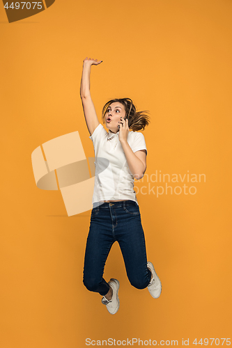 Image of Full length of pretty young woman with mobile phone while jumping