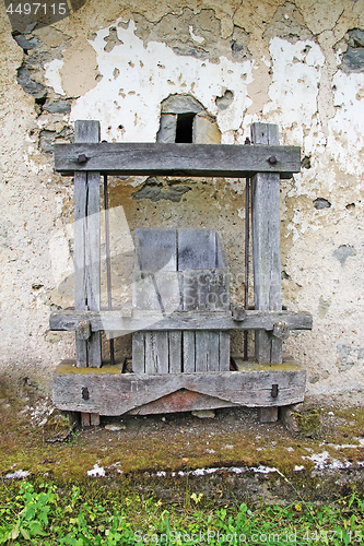 Image of Old Antique wooden wine press in front of the rusty wall