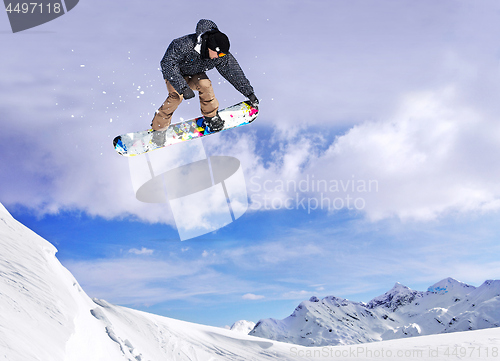 Image of Snowboarder jumping through air with blue sky in background