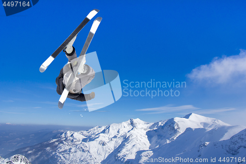 Image of Extreme Jumping skier at jump above mountains at sunny day