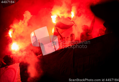 Image of football hooligans with mask holding torches in fire