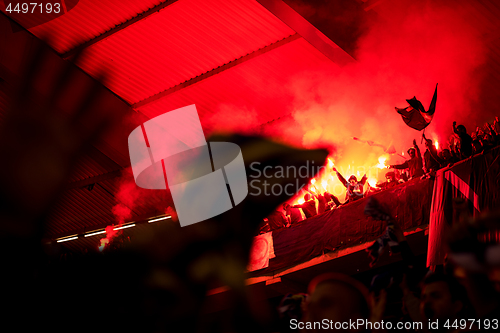 Image of football hooligans with mask holding torches in fire