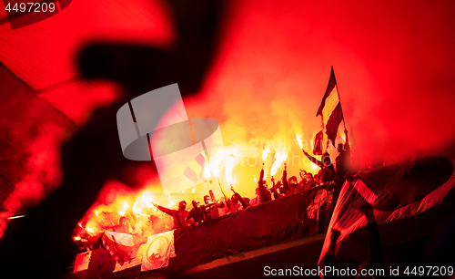 Image of football hooligans with mask holding torches in fire