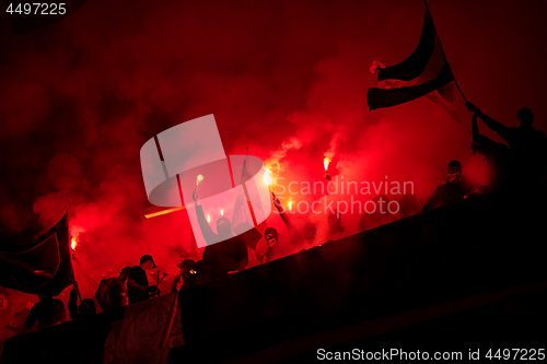 Image of football hooligans with mask holding torches in fire