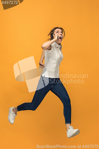 Image of Full length of pretty young woman with mobile phone while jumping