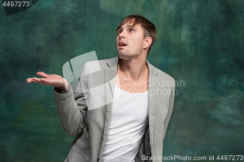 Image of The happy man standing and smiling against studio background.