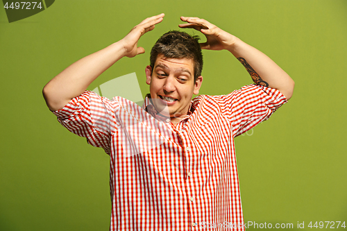 Image of Beautiful male half-length portrait isolated on blue studio backgroud. The young emotional surprised man