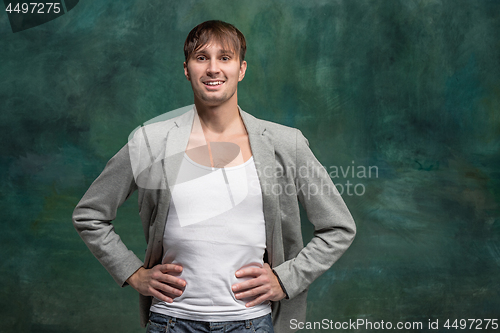 Image of The happy man standing and smiling against studio background.