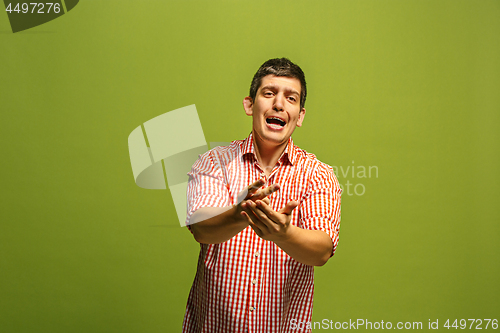 Image of Beautiful male half-length portrait isolated on green studio backgroud. The young emotional surprised man