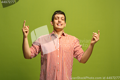 Image of Beautiful male half-length portrait isolated on green studio backgroud. The young emotional surprised man