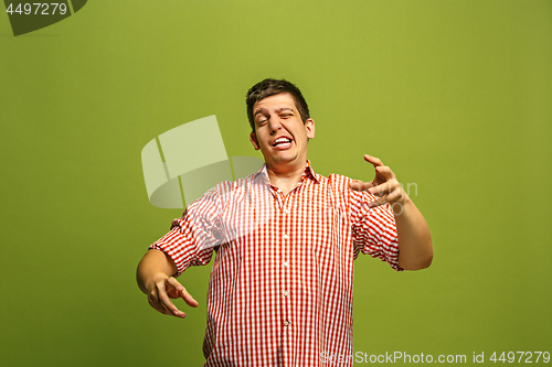 Image of Beautiful male half-length portrait isolated on green studio backgroud. The young emotional surprised man