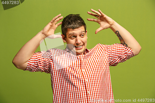 Image of Beautiful male half-length portrait isolated on blue studio backgroud. The young emotional surprised man