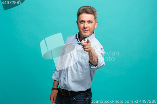 Image of The happy business man point you and want you, half length closeup portrait on blue background.