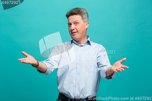 Image of Beautiful male half-length portrait isolated on blue studio backgroud. The senior emotional surprised man