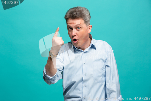 Image of Beautiful male half-length portrait isolated on blue studio backgroud. The senior emotional surprised man