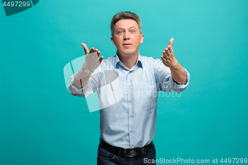 Image of Beautiful male half-length portrait isolated on blue studio backgroud. The senior emotional surprised man