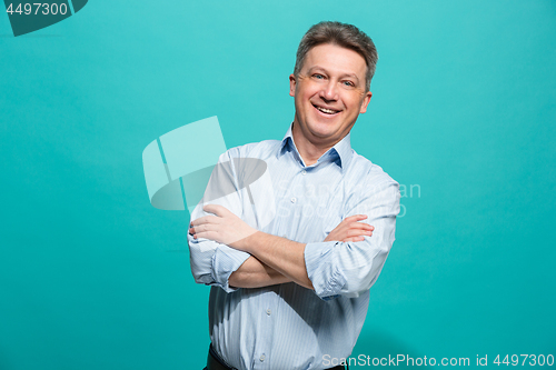 Image of The happy businessman standing and smiling against blue background.