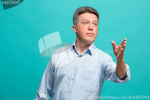 Image of Beautiful male half-length portrait isolated on blue studio backgroud. The senior emotional surprised man