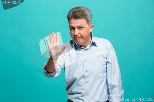 Image of Beautiful male half-length portrait isolated on blue studio backgroud. The senior emotional surprised man