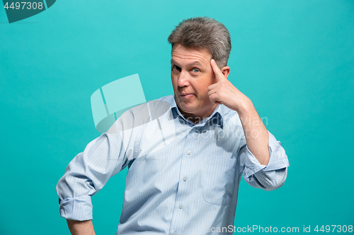 Image of Beautiful male half-length portrait isolated on blue studio backgroud. The senior emotional surprised man