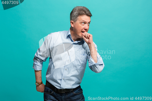 Image of Beautiful male half-length portrait isolated on blue studio backgroud. The senior emotional surprised man