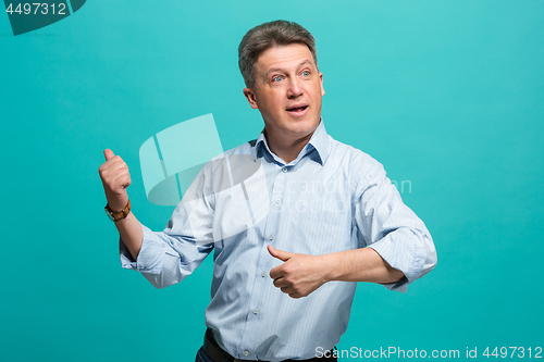 Image of Beautiful male half-length portrait isolated on blue studio backgroud. The senior emotional surprised man