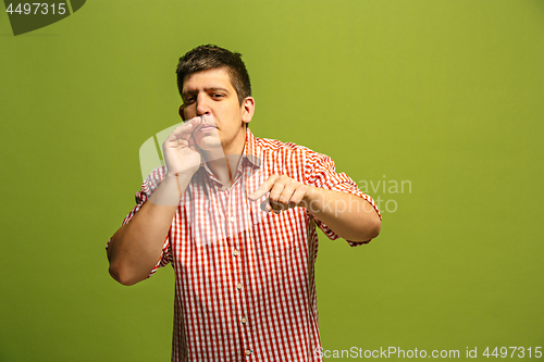Image of The young man whispering a secret behind her hand over green background