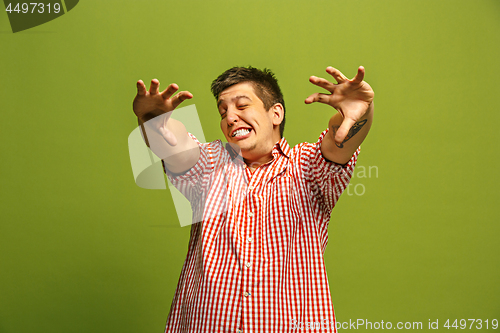 Image of The young emotional angry man screaming on green studio background