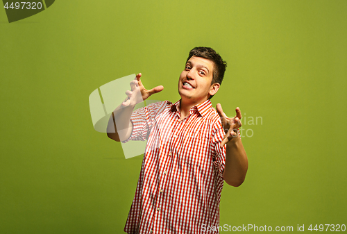 Image of The young emotional angry man screaming on green studio background