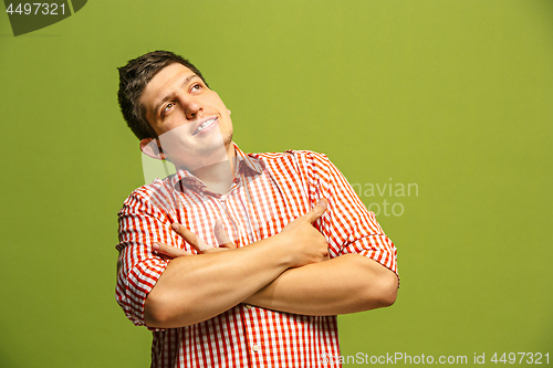 Image of Let me think. Doubtful pensive man with thoughtful expression making choice against green background